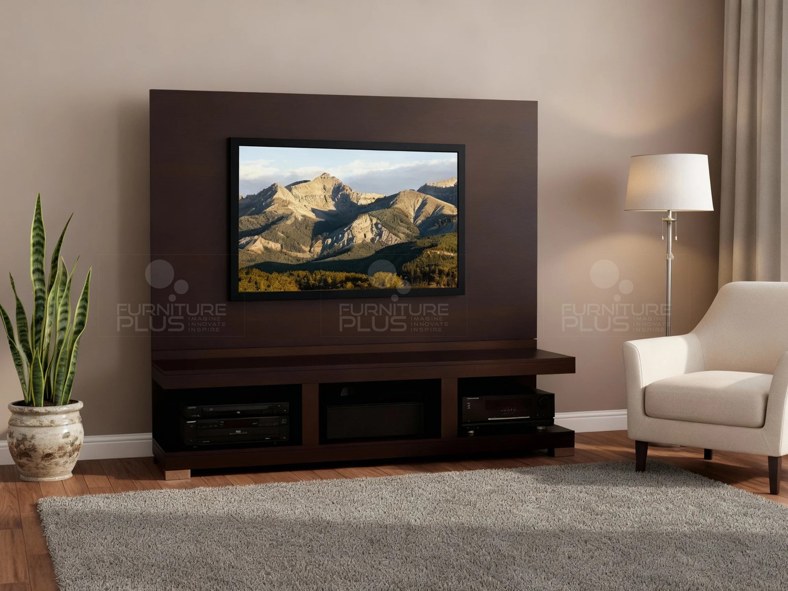 A contemporary living room featuring a dark espresso Mahogany wood Caesar media wall unit. It consists of a wide console with three open shelves holding media components, and a large vertical back panel with a flat-screen television mounted centrally, displaying a mountain landscape. The unit is set against a light brown wall, flanked by a tall potted snake plant on the left and a cream armchair with a floor lamp on the right. A large gray shag rug covers the hardwood floor