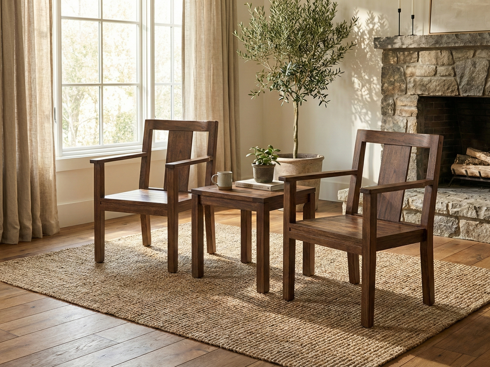 Two matching Easton Easy Chairs, made of dark-stained Mahogany wood with a modern, geometric design and open backs, are placed on a woven jute rug. The chairs face a square wooden side table holding a mug and a potted plant. The setting is a cozy living room with a large window draped in neutral curtains, a tall potted olive tree, and a rustic stone fireplace with wood stacked inside