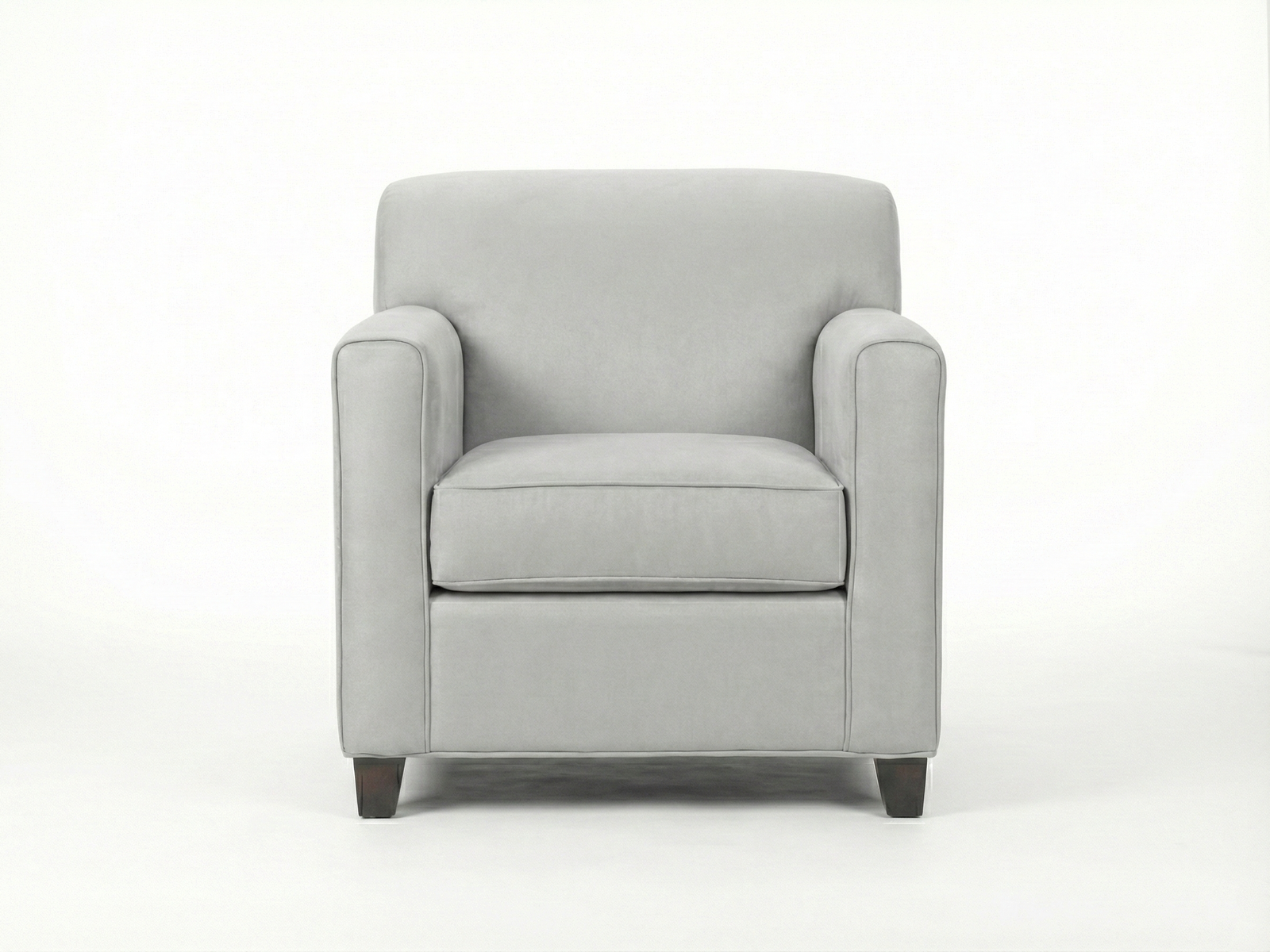 Front view of the Evone Arm Chair, a contemporary, fully upholstered easy chair in a soft light gray fabric. The chair features a squared back, straight track arms with subtle rounding, and a thick, removable seat cushion with piping detail. It sits on short, dark wooden block feet against a plain white background