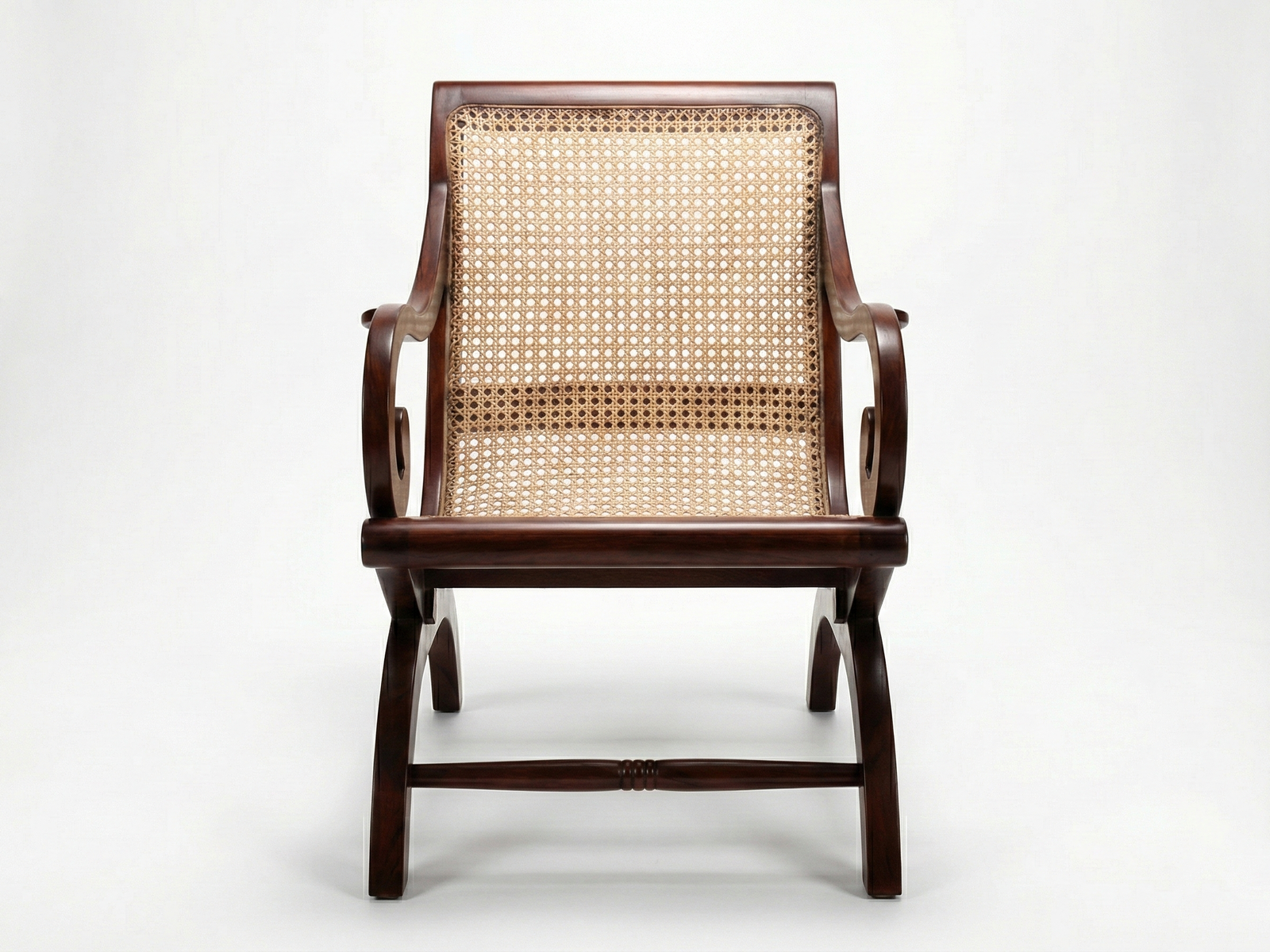 Front view of the Geoffry Easy Chair, a highly stylized and exotic armchair made of polished dark brown wood. The chair features a curved frame with dramatically scrolled armrests and legs, creating an X-shape base. Both the back and seat are panelled with woven cane (rattan). The chair has a low profile and is photographed against a plain white background