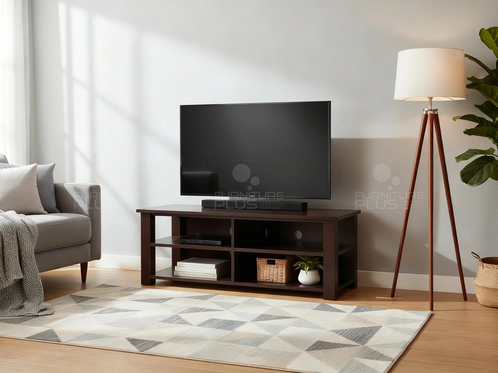 A cozy modern living room featuring a dark espresso wood Saturn TV stand with open shelving, holding a flat-screen television and a soundbar. The shelves are styled with media devices, a woven basket, and a small potted plant. The unit is placed on a wood floor with a geometric gray and white area rug, next to a gray sofa on the left and a tripod-style floor lamp on the right
