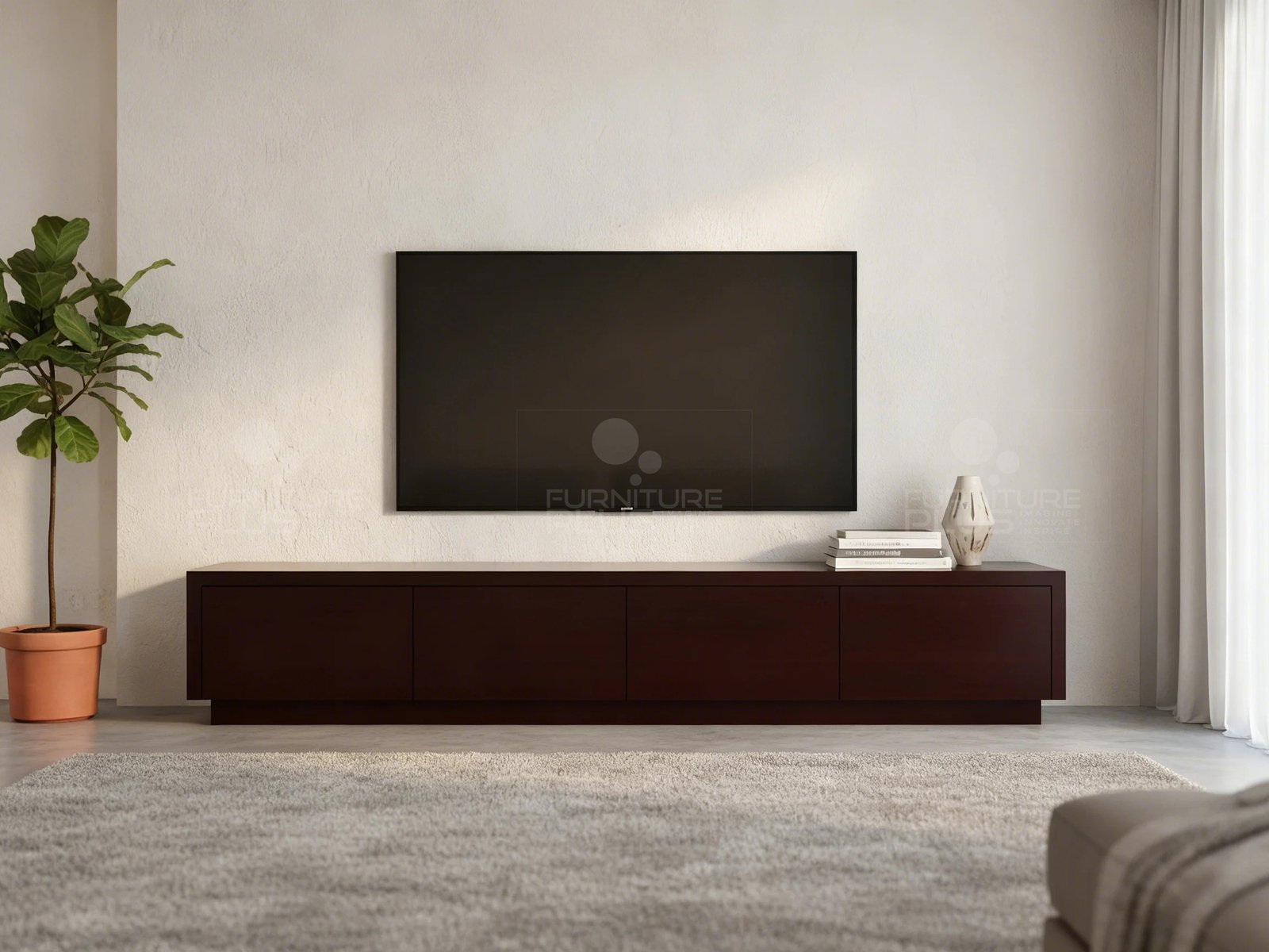 A minimalist living room featuring a long, extra-low Shrek TV console in a dark espresso Mahogany wood finish, with four handleless storage compartments across the front. A large flat-screen television is mounted on the textured white wall above the unit. The console is decorated with a small stack of books and a light-colored vase. A potted fiddle-leaf fig tree stands to the left, and a plush light-colored area rug covers the floor in the foreground