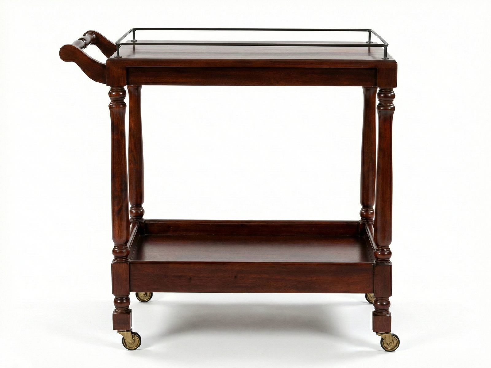 Front side view of a classic Tiara dark Mahogany wood tea trolley on a white background. It features elegant turned legs, a top shelf with a thin metal guard rail, and a bottom tray shelf with raised wooden edges. The cart includes a curved wooden push handle on one side and sits on vintage-style brass caster wheels