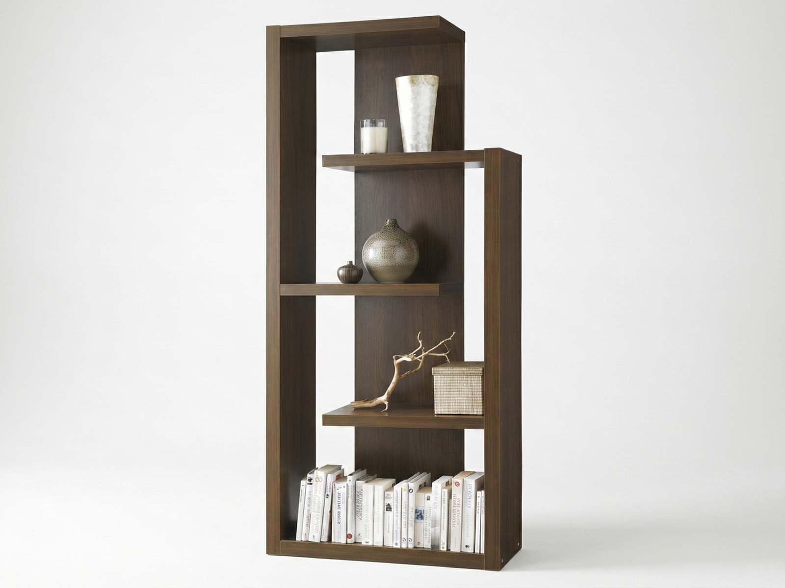 Side view of a modern, Mahogany wood Aldgate display unit with an asymmetrical, open-back design. The shelves are staggered at different heights and hold decorative items including vases, a candle, driftwood, a woven box, and a row of books on the bottom shelf