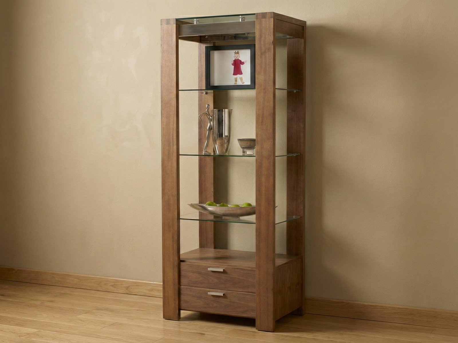 A tall, modern display unit or display cabinet made Mahogany wood. The unit has an asymmetrical, staggered, and geometric design, creating several open, rectangular shelves of varying sizes. The shelves are styled with various decorative items, including wine glasses, metallic vases, reddish-brown vases, books, clear glass containers, and bowls